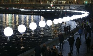 People walk under the lit balloons installation along the river Spree in Berlin